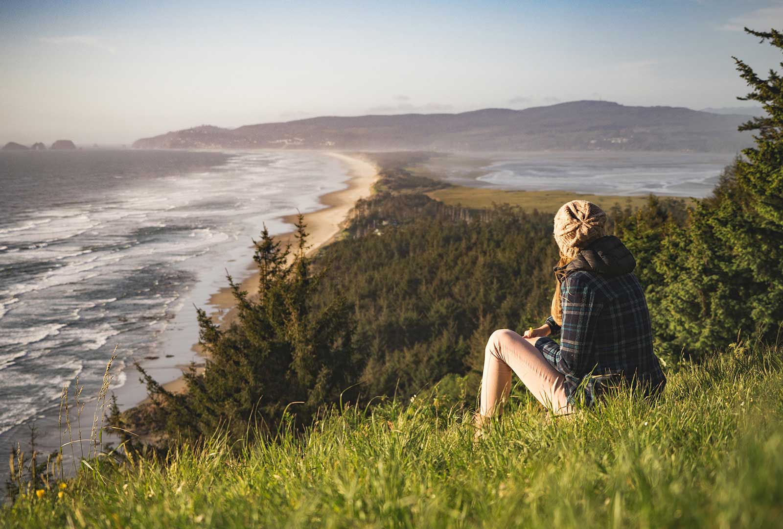 woman sitting on coastal hillside looking into distance